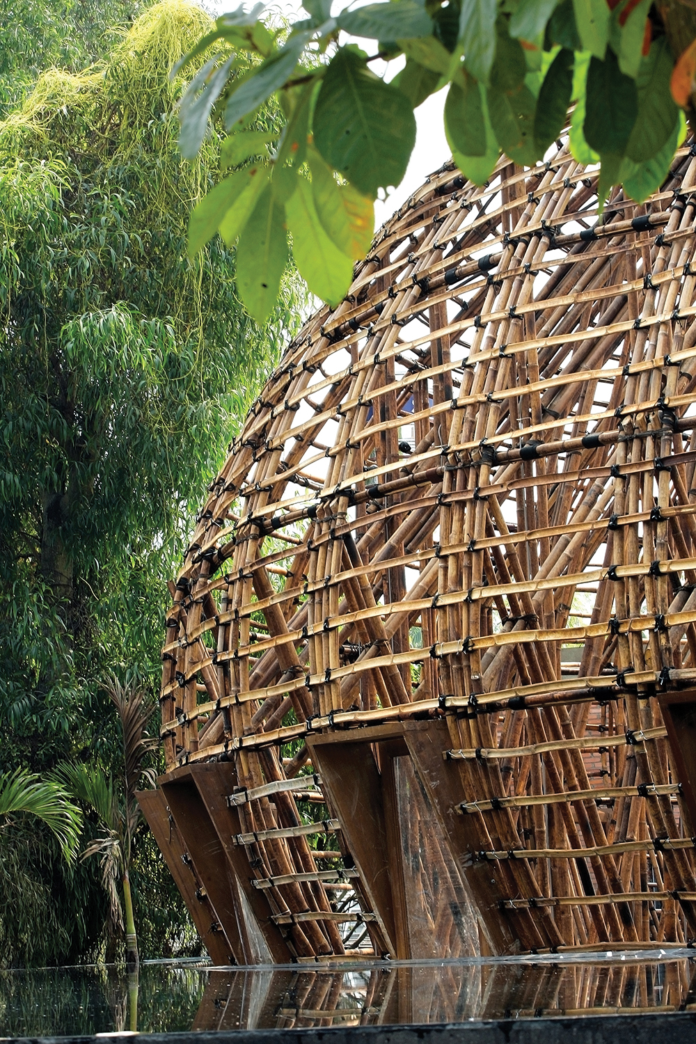 Without using any metal fixtures, 48 prefabricated units of a 10M tall and 15M wide bamboo arch were bound together with rope. This is their first experiment with systemized bamboo construction. Image © Vo Trong Nghia Architects