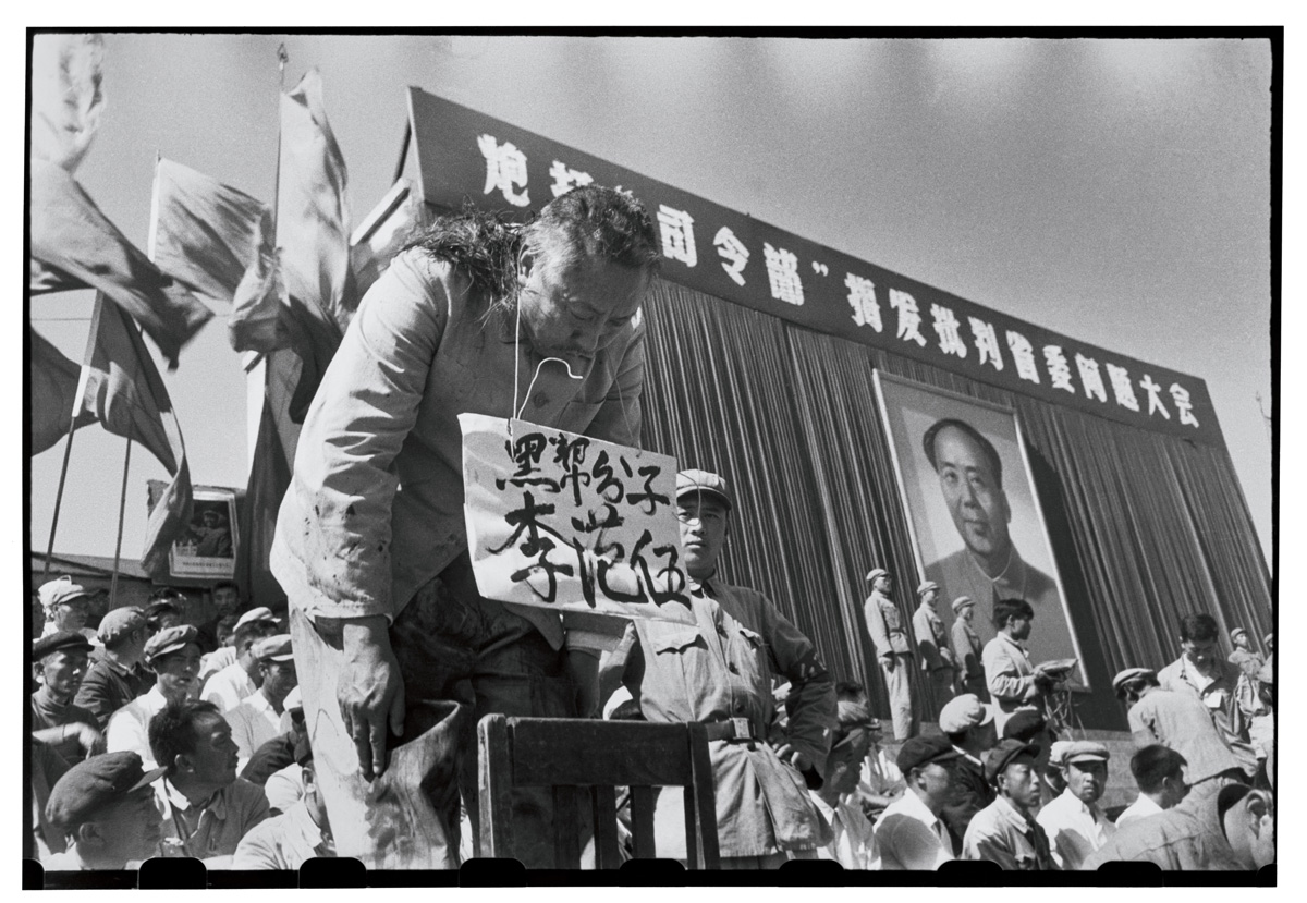 Accused of bearing a resemblance to Mao, Heilongjiang province Governor Li Fanwu’s hair is brutally shaved, torn by zealous young Red Guards and made to bow for hours, clippings of his hair stuffed down his neck and shirt by an infuriated Red Guard. The banner behind him reads, "Bombard the Headquarters! Expose and denounce the provincial Party committee." Harbin, 12 September 1966, Image courtesy of Li Zhensheng